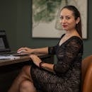 Confident businesswoman in stylish dress working on a laptop at her desk.